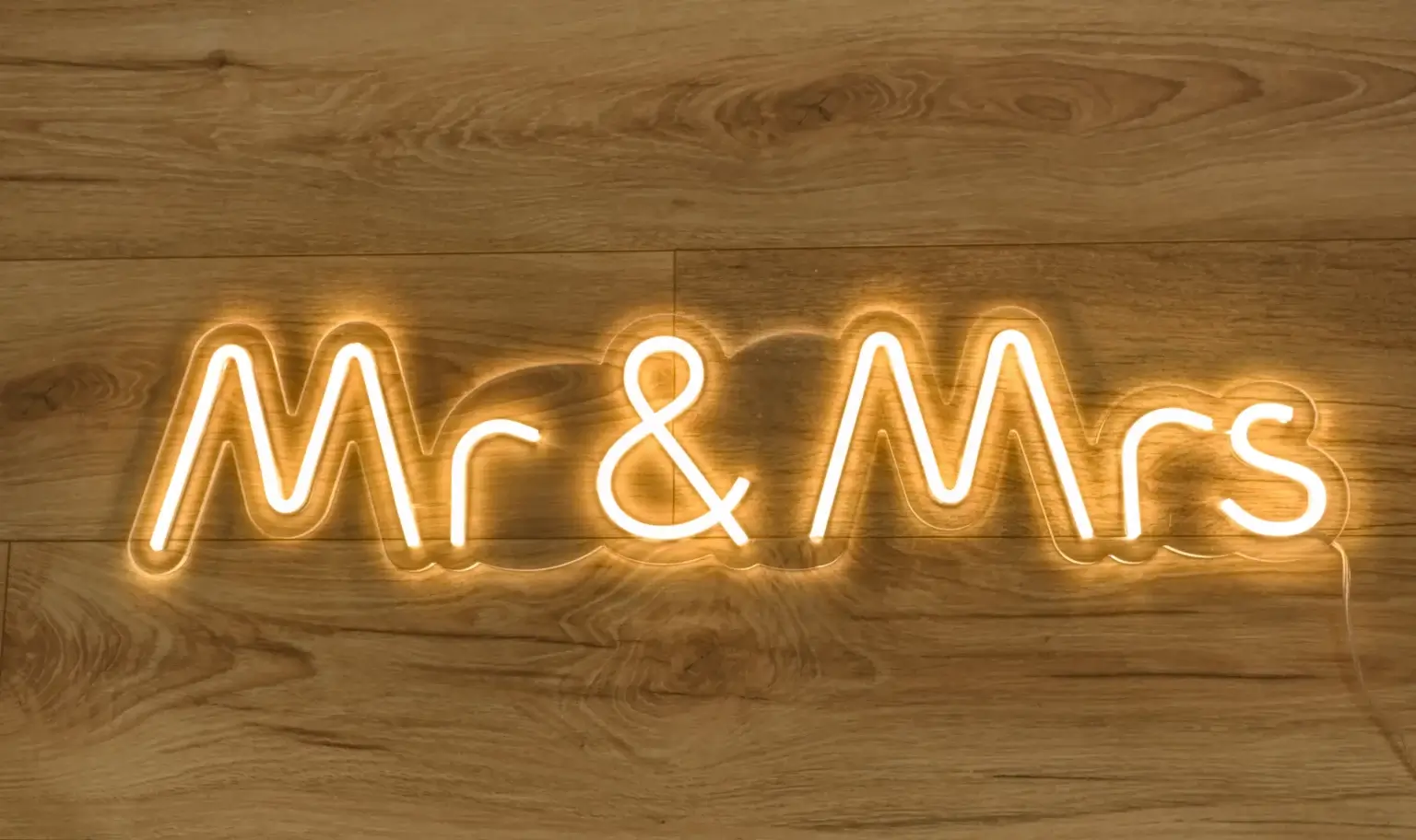 LED neona uzraksts Mr & Mrs siltā baltā gaismā uz koka fona
