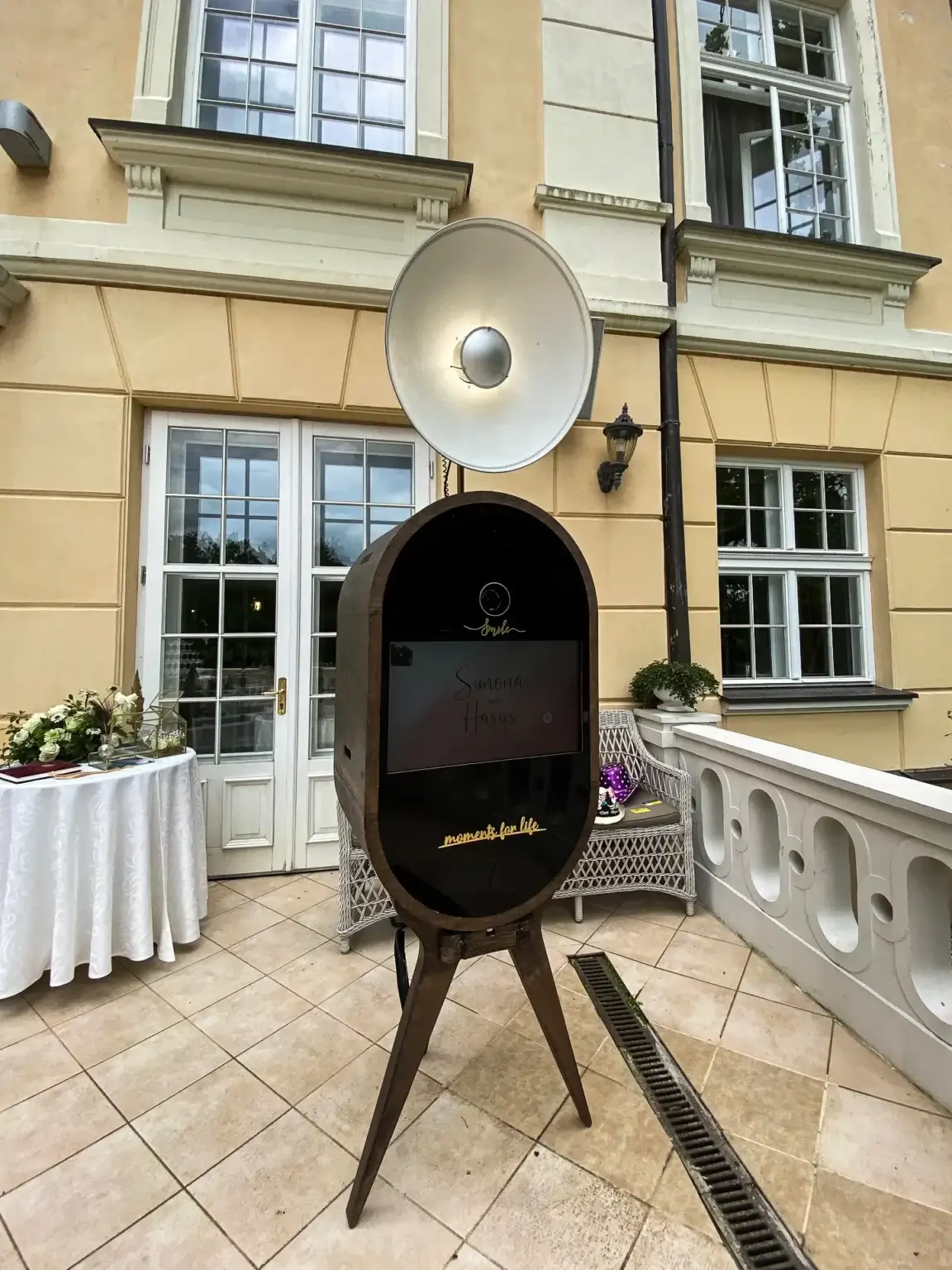 Koka vintage foto kaste ar gaismas lietussargu uz muižas terases pie baltas balustrādes