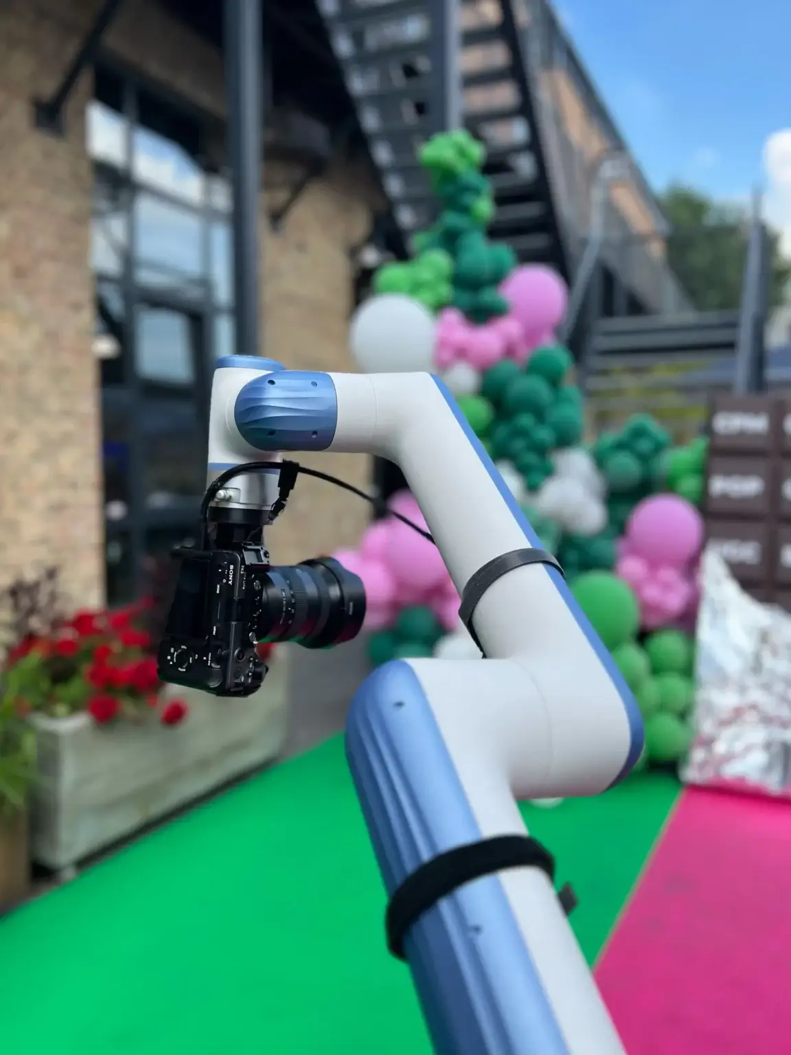 GlamBot robota roka ar kameru āra pasākumā pie balonu virtenes