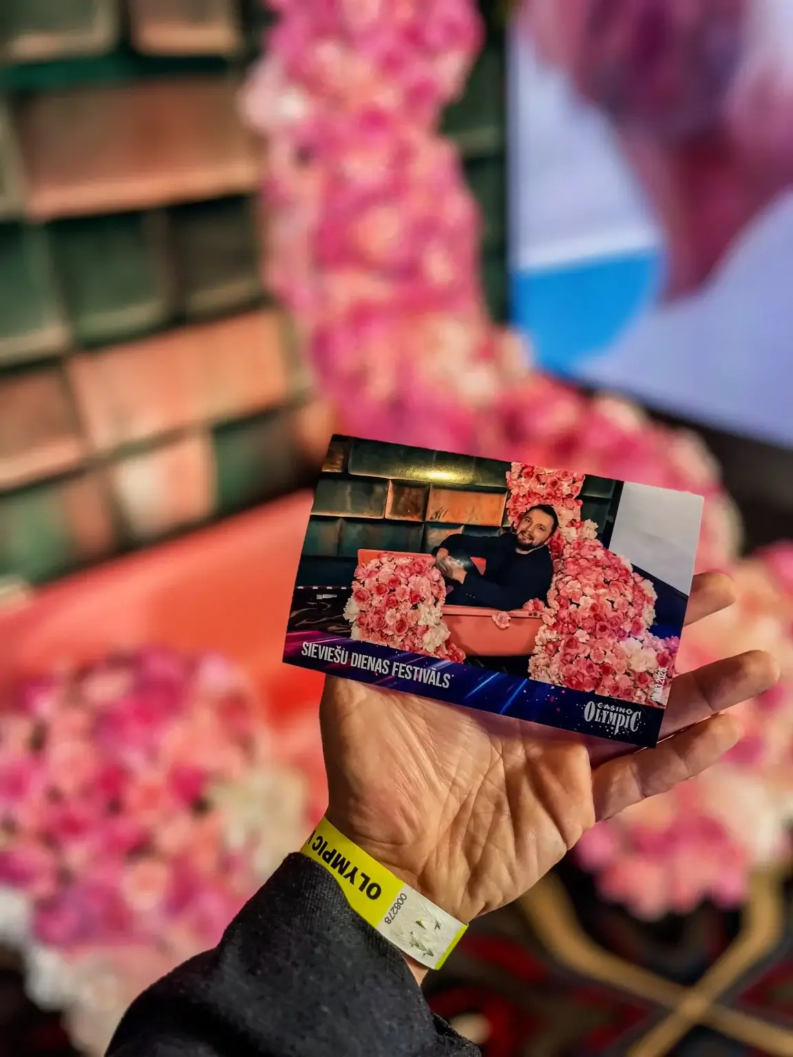 Roka tur izdrukātu bildi no ziedu foto zonas